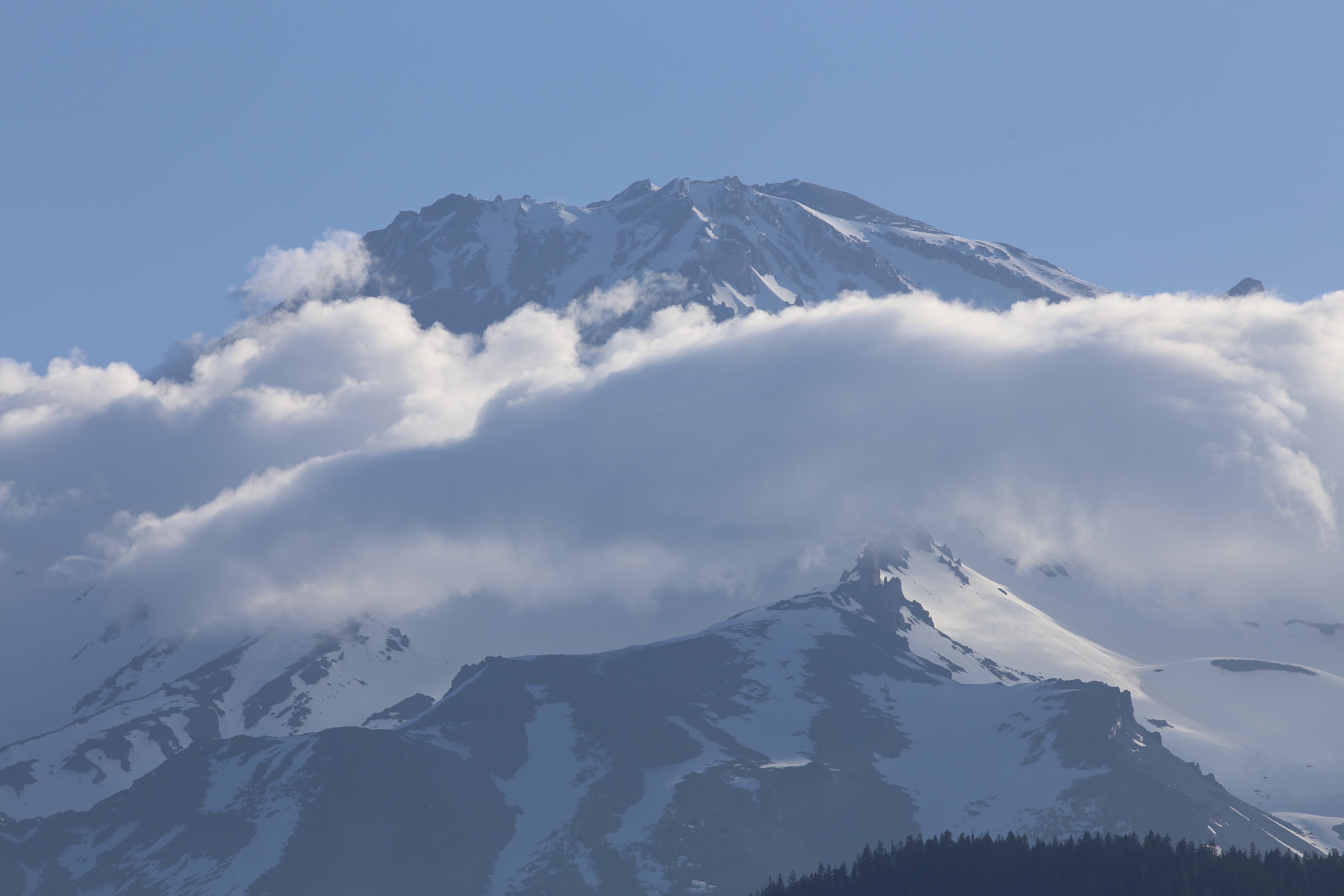 Telephoto view of Mt Shasta's rocky summit with dramatic lenticular clouds wrapping around the mid-section of the mountain